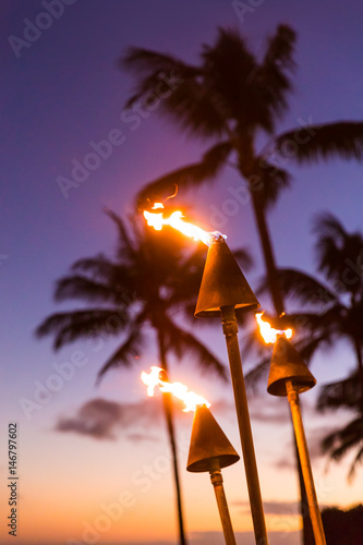 Fototapeta Hawaii sunset with lit tiki torches