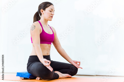 Beautiful young woman practicing yoga at home in the lotus position.