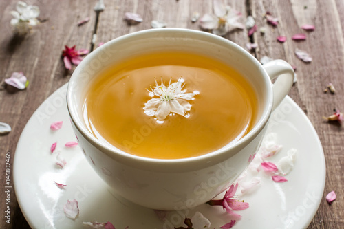 cup of green flower tea and blossoming cherry flowers