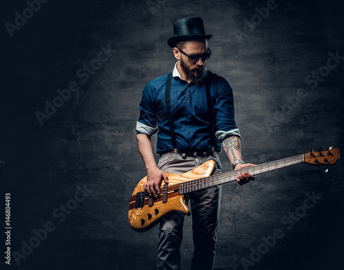 Fotografie Studio portrait of the hipster bass player dressed in cylinder hat