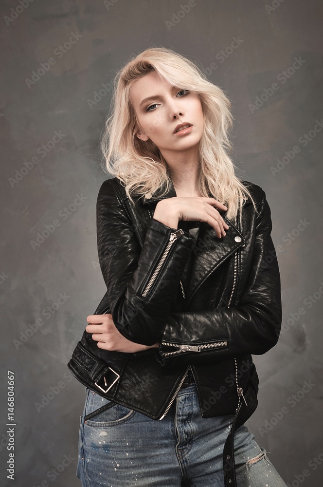 Blonde girl dressed in blue jeans and a black leather jacket. Stock ...