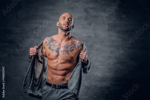 Fotografija Shaved head tattooed male dressed in a grey jacket on a naked torso
