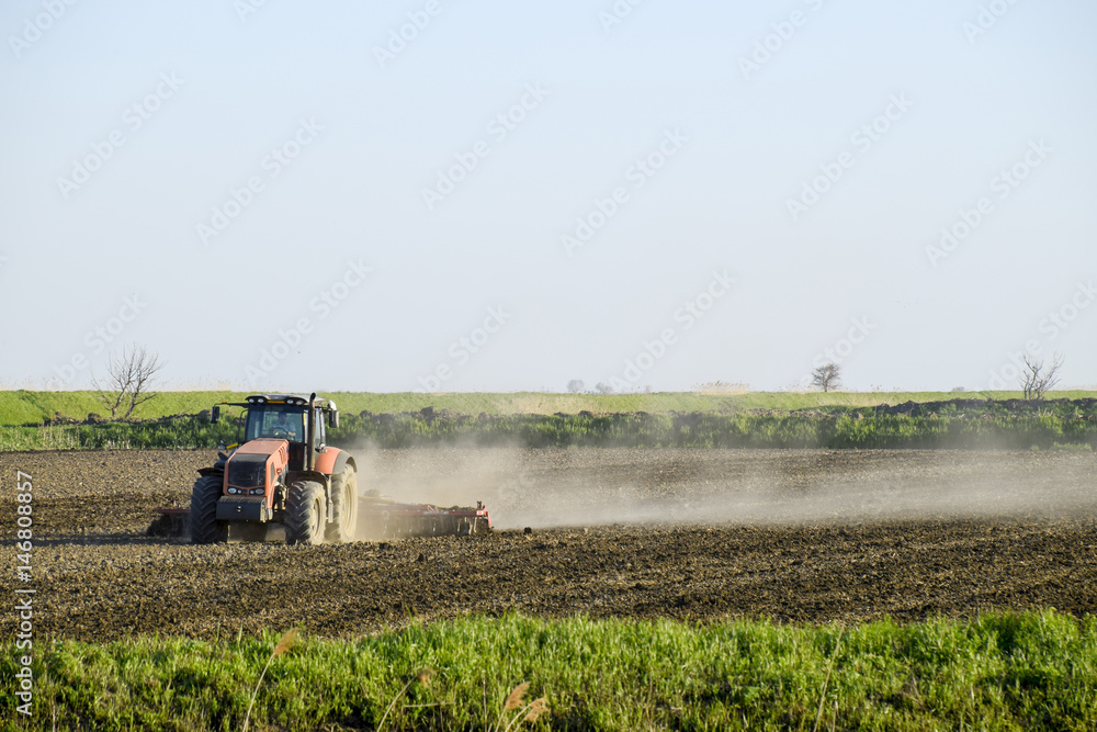 Fototapeta premium A tractor with a plow lays the soil. Soil cultivation on the fie
