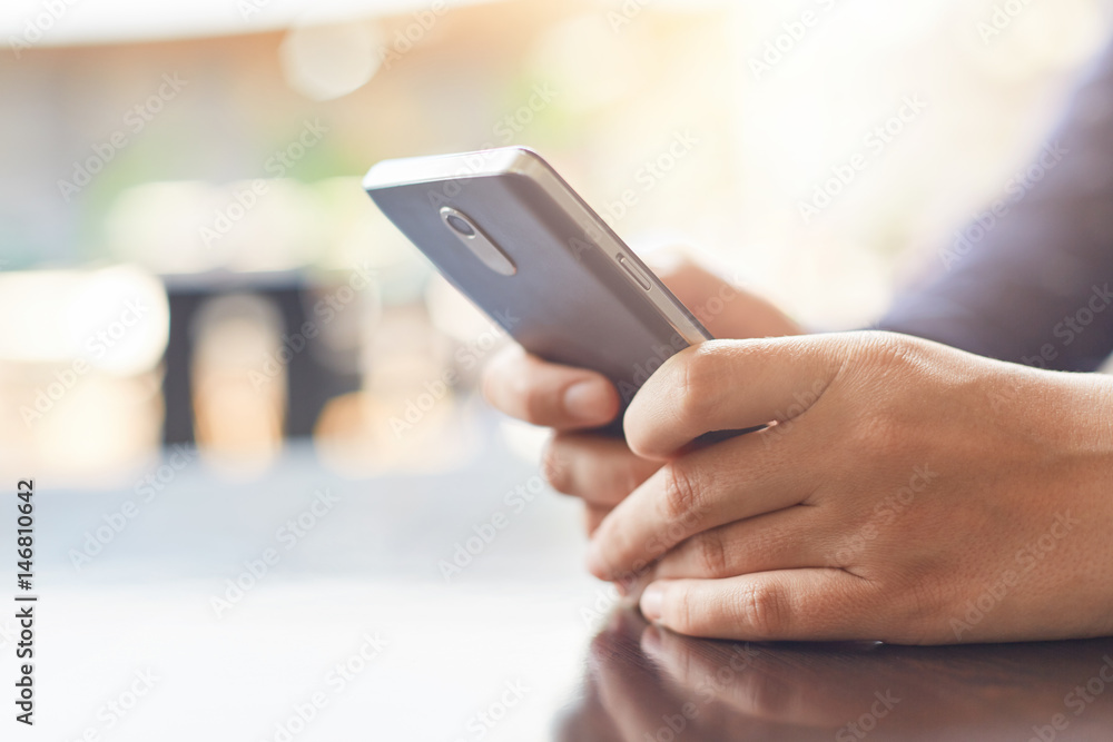 Cropped shot of woman`s hands holding mobile phone checking her e-mail online in cafe using high-speed internet connection.Technology and communication concept.