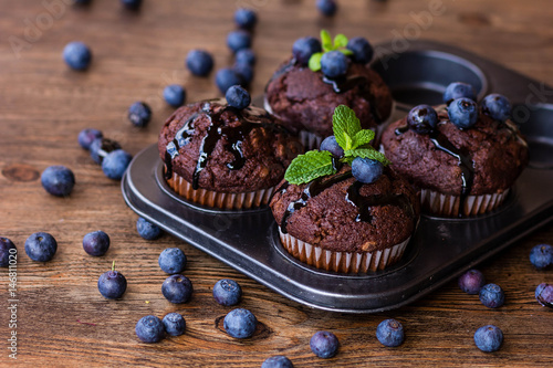 Wallpaper Mural Chocolate muffins with chocolate syrup, blueberries and mint in a wooden background Torontodigital.ca