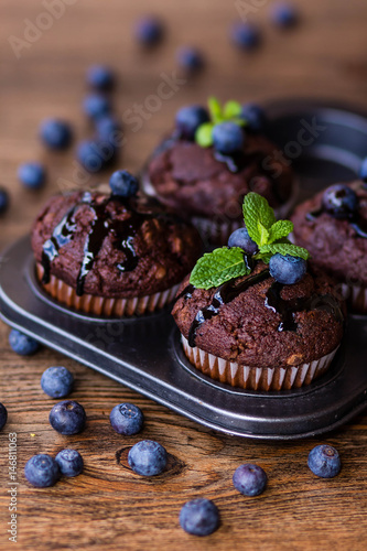 Wallpaper Mural Chocolate muffins with chocolate syrup, blueberries and mint in a wooden background Torontodigital.ca