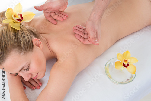 Woman getting massaging treatment over white background in spa