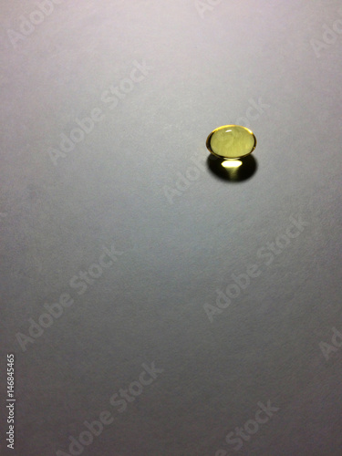 Minimalistic shot of fish oil capsule laying on paper background. Rule of thirds used.