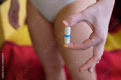 The girl is holding a tampon in her hands. A convenient means of hygiene during menstruation