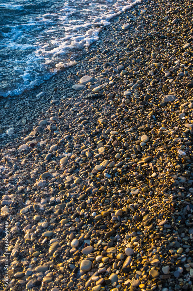 sea pebble beach with multicoloured stones, waves with foam sea pebble beach with multicoloured stones, waves with foam