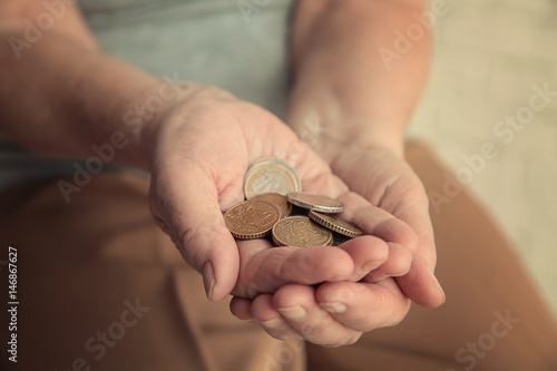 Hands of senior woman with coins, closeup. Poverty concept