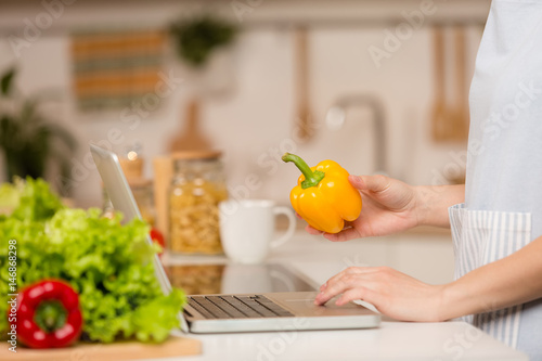Young Woman standing in kitchen with laptop and looking recipes. Food concept. Close-up.