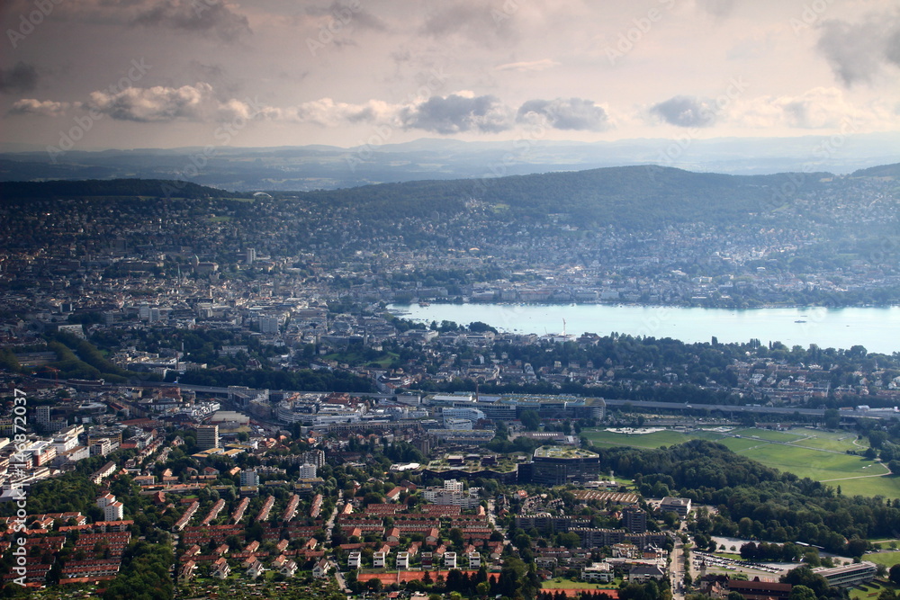 Fototapeta premium Cityscape of Zurich, the colorful rooftops of the city centre with Lake Zurich and forested Adlisberg, seen from Uetliberg, Switzerland, Europe