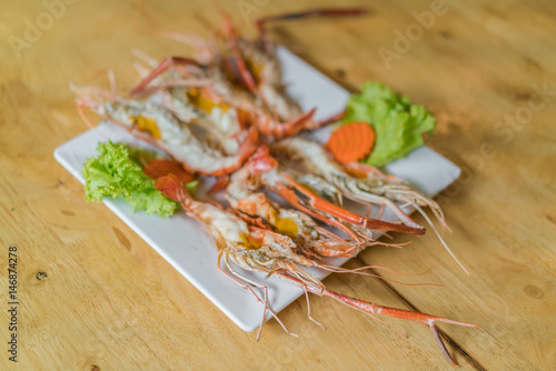 shrimps grilled served in plate on wood table .