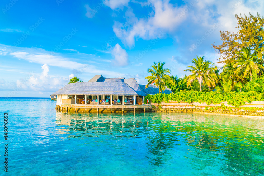 Beautiful water villas in tropical Maldives island at the sunrise time .