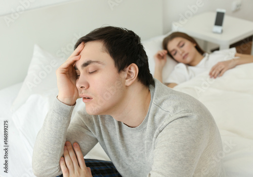 Sleepy young man sitting on...