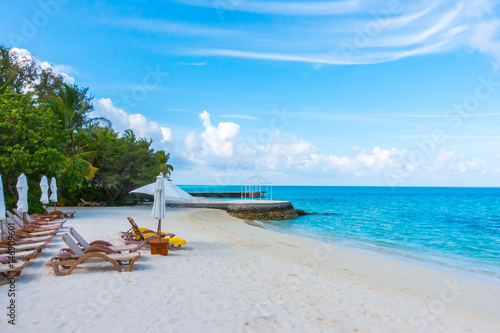 Beach chairs with umbrella at Maldives island with white sandy beach and sea . © jannoon028