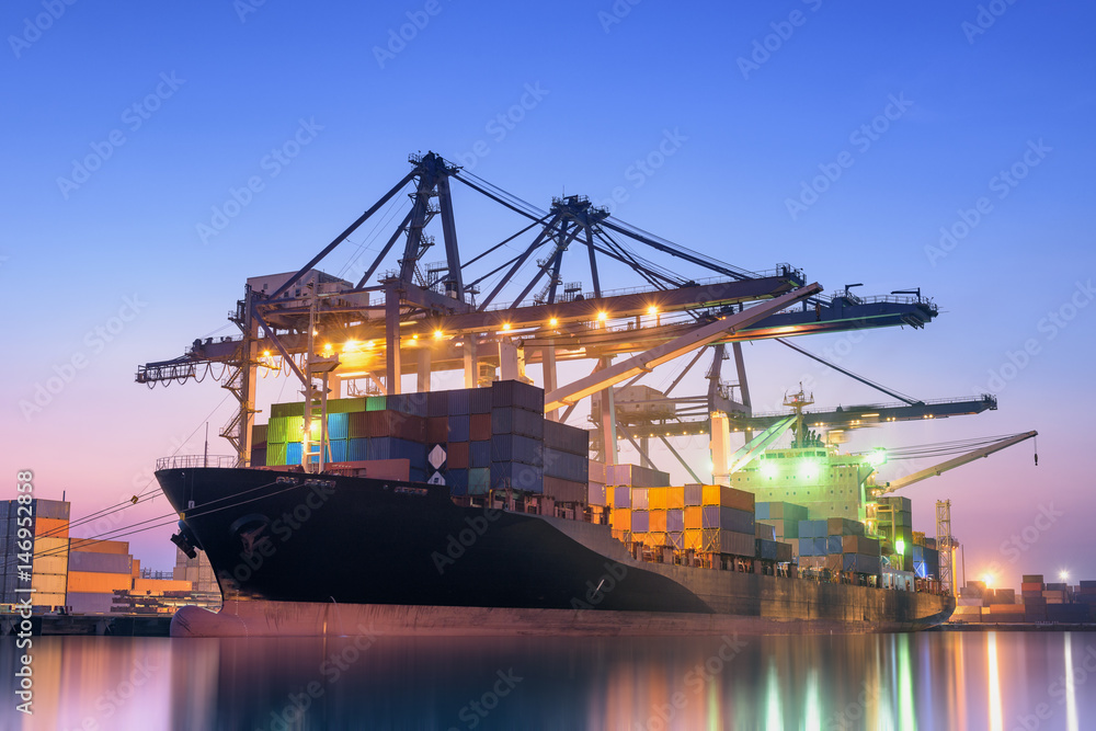 Fototapeta premium Cargo ship unloading container at twilight.