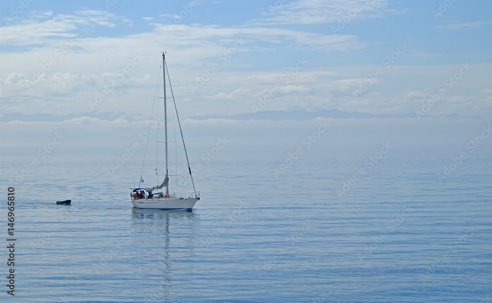 Sailboat gliding with calm blue ocean water with blue sky background and has copy space room
