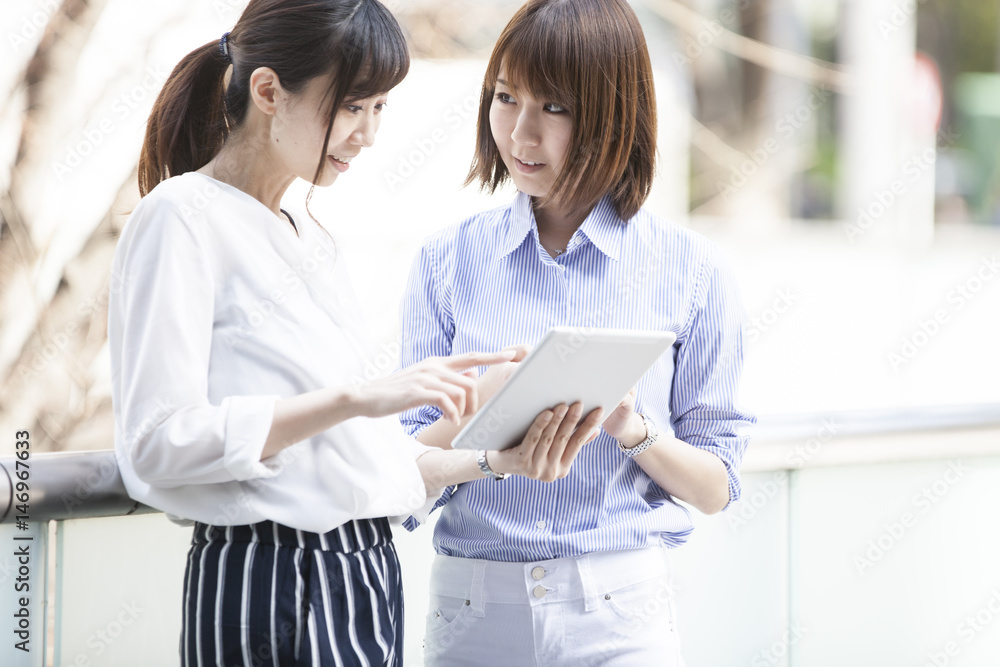 Two women are smiling while watching the tablet Two women are smiling while watching the tablet