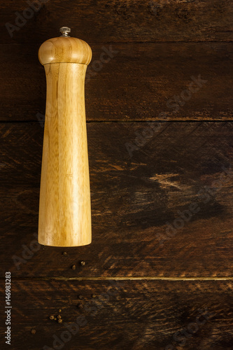 Vintage pepper mill on dark background with peppercorns