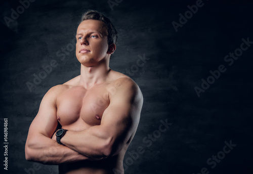 Studio portrait of shirtless athletic male with crossed arms.
