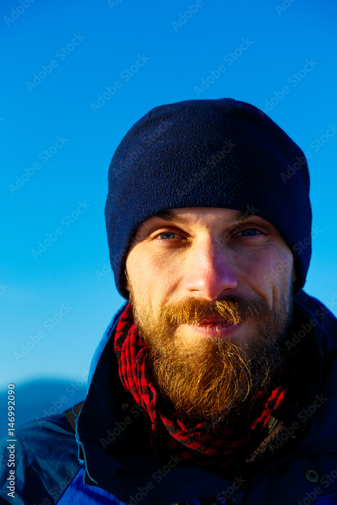 freezing young man with winter cap and blue sky on the background. freezing young man with winter cap and blue sky on the background.