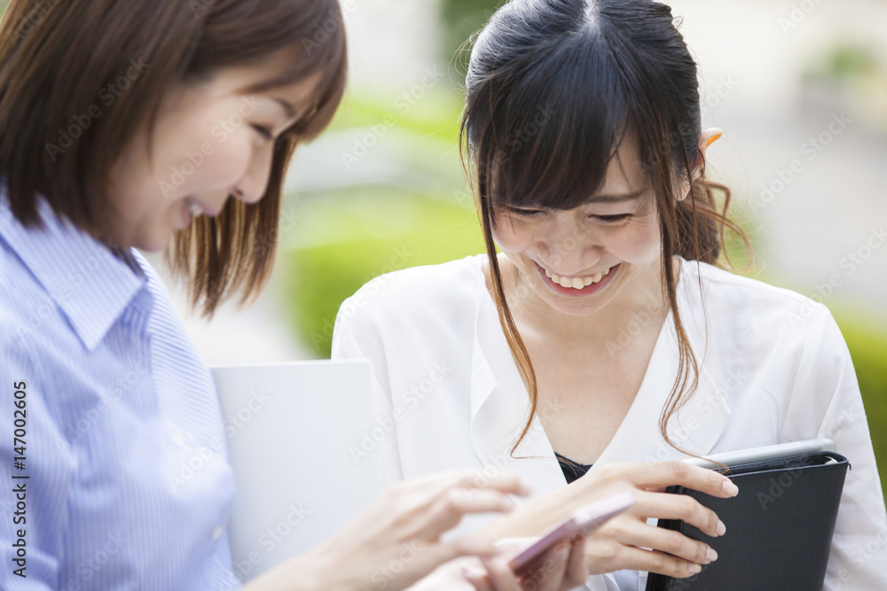 Women are smiling while watching smartphone Women are smiling while watching smartphone