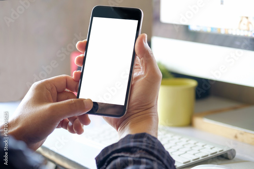 Man using Smartphone while working on desk with blurred office background
