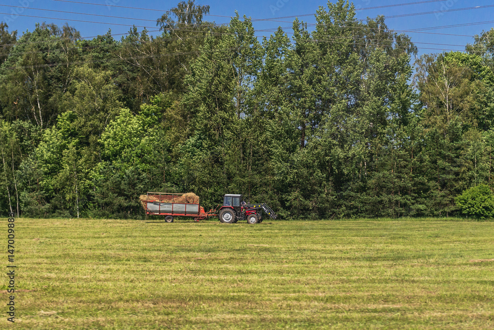 Fototapeta premium Tractor on a field - rural scene in Latvia
