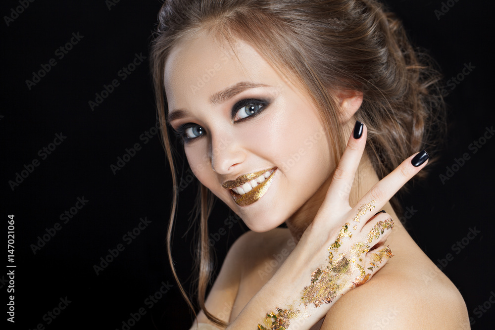 Obraz premium Beauty Woman Portrait. Professional Makeup and Manicure with gold foil glitter, smokey eyes. Black colors. Copy-space. Smyle and make peace by fingers