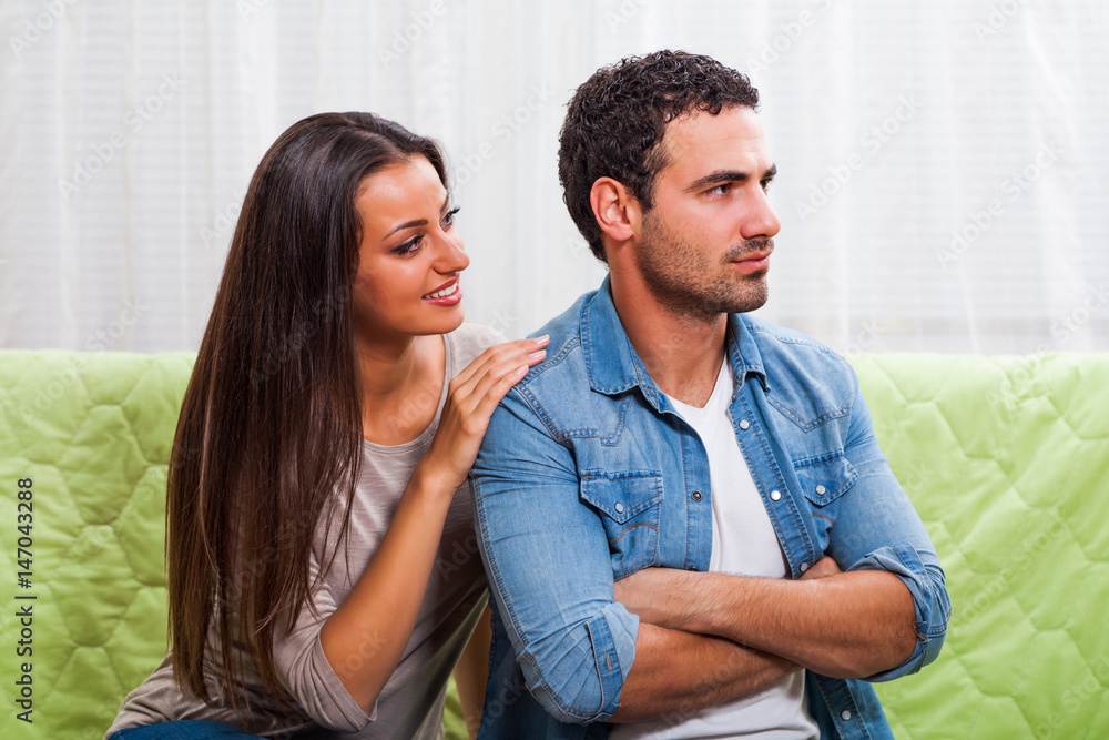 Young couple is sitting on sofa at home. Man is angry. Young couple is sitting on sofa at home. Man is angry.