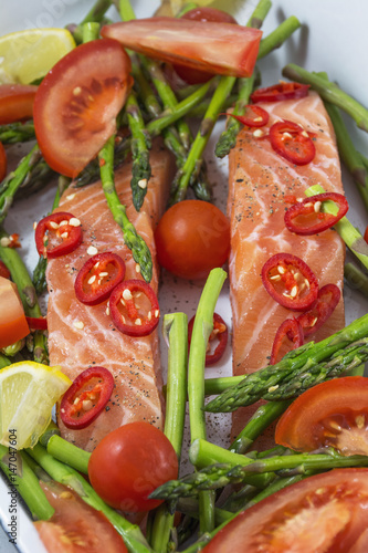 Two pieces of salmon with green asparagus, tomato and red pepper