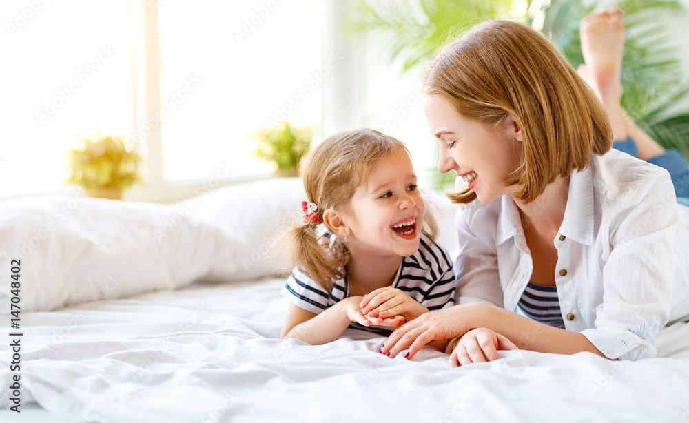 Happy family mother and child daughter laugh in bed Happy family mother and child daughter laugh in bed