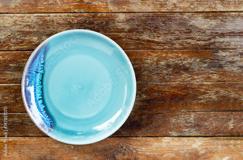 Top view of blue empty ceramic plate on wooden background with copy space.