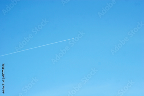 The airplane is flying under the blue sky