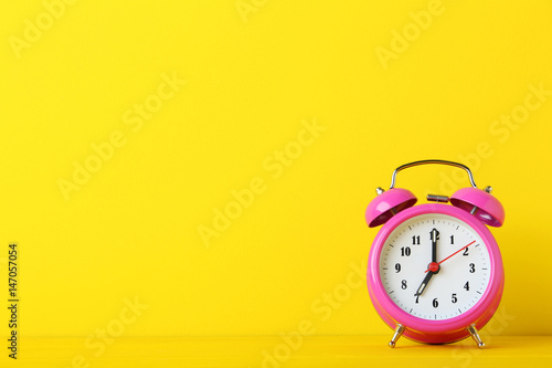Pink alarm clock on yellow background