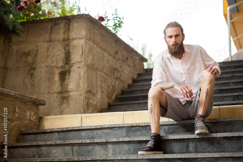 Tattoed and bearded guy posing outdoor in the city