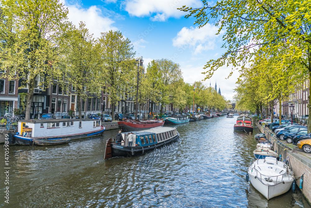 Amsterdam, The Netherlands, April 22, 2017: Local and tourist walking on the Keizersgracht Canal in spring in the Jordaan area with boats, bikes and cars