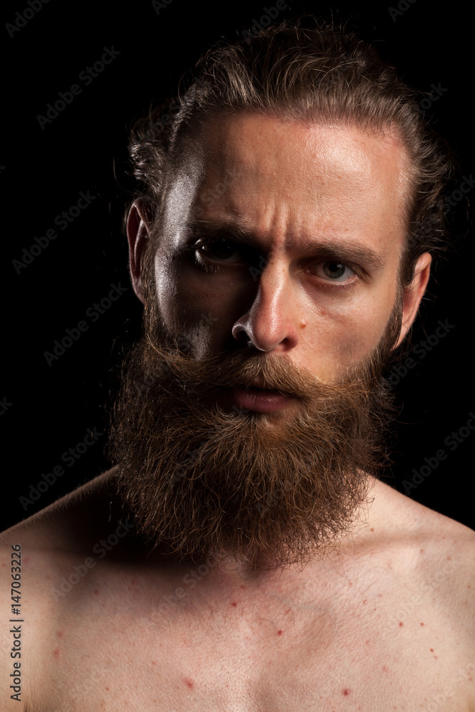 Obraz premium Tattooed bearded hipster on black background in studio photo. Expression and fashion