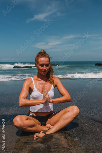 Young attractive woman practicing yoga with Namaste on the beach of Indian ocean, Indonesia, Bali