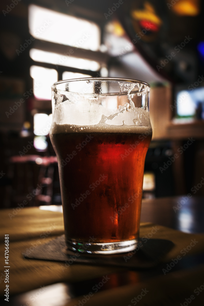 Beautiful glass of cold tasty dark beer in bar. Dark Background. Closeup. Selective focus.