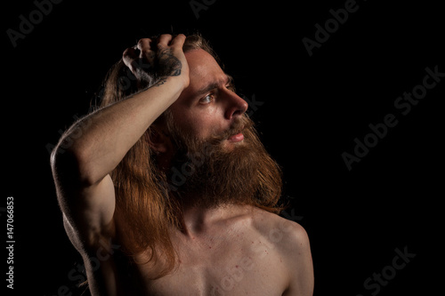 Cool looking tattooed bearded hipster on black background in studio photo. Expression and fashion