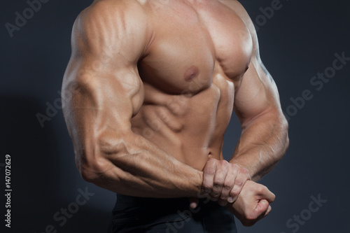 Portrait of strong healthy handsome Athletic Man Fitness Model posing near dark gray wall © putilov_denis