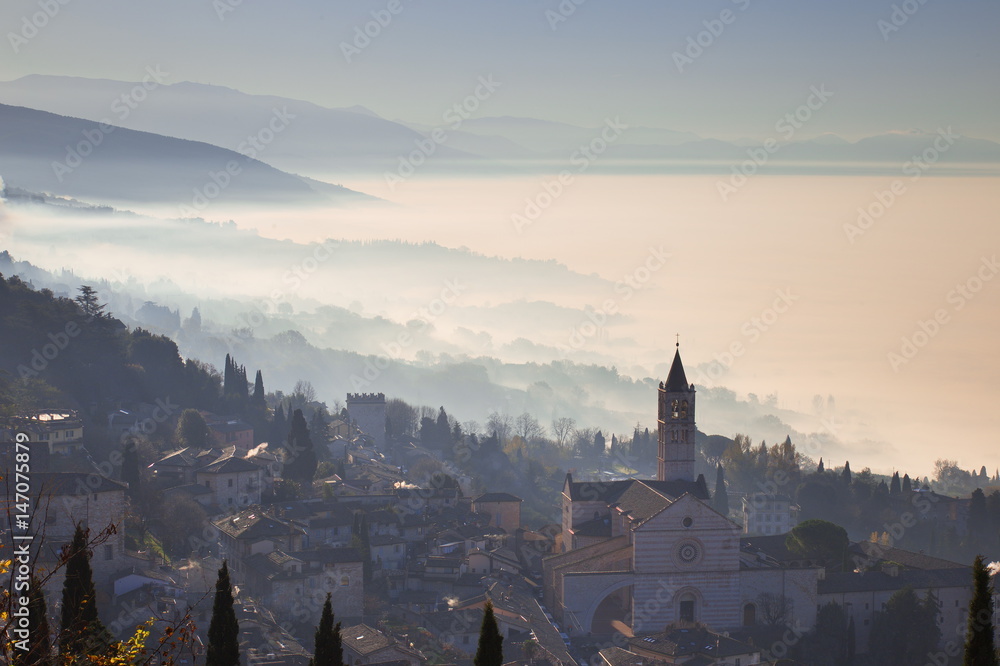 Beautiful view of the St. Clare church in Assisi (Italy) with fog below and in the background