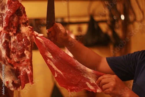Close up butcher cutting raw meat on traditional market