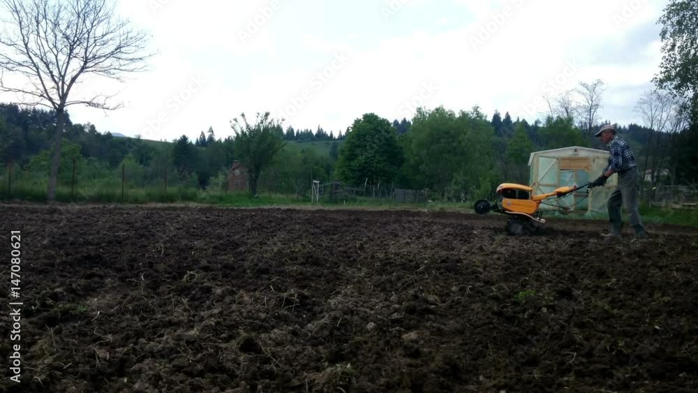 Man plowing with cultivator, garden preparation Man plowing with cultivator, garden preparation