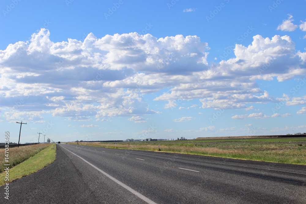Highway with crop land and cloudy sky