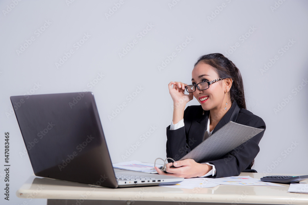 Businesswoman sitting at desk and hand holding glasses in office. Businesswoman sitting at desk and hand holding glasses in office.