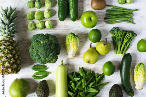 One colour, healthy eating concept, green fruits and vegetables arranged in grid, apples, pears, broccoli, peas, cauliflower, beans, asparagus, kiwi, avocado, pineapple on white table, selective focus